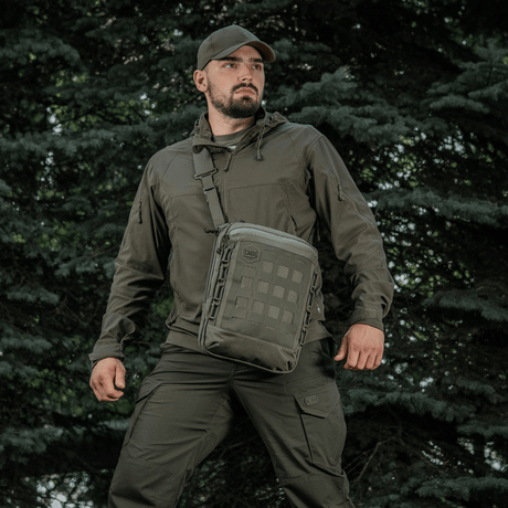 Person med M-Tac Tablet Bag Laser Cut Hex taske i skovmiljø.