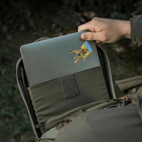 Person sætter laptop ind i M-Tac Tablet Bag Laser Cut Hex med Laser Cut MOLLE, lavet af Cordura materiale til tablet og skjulte våben.