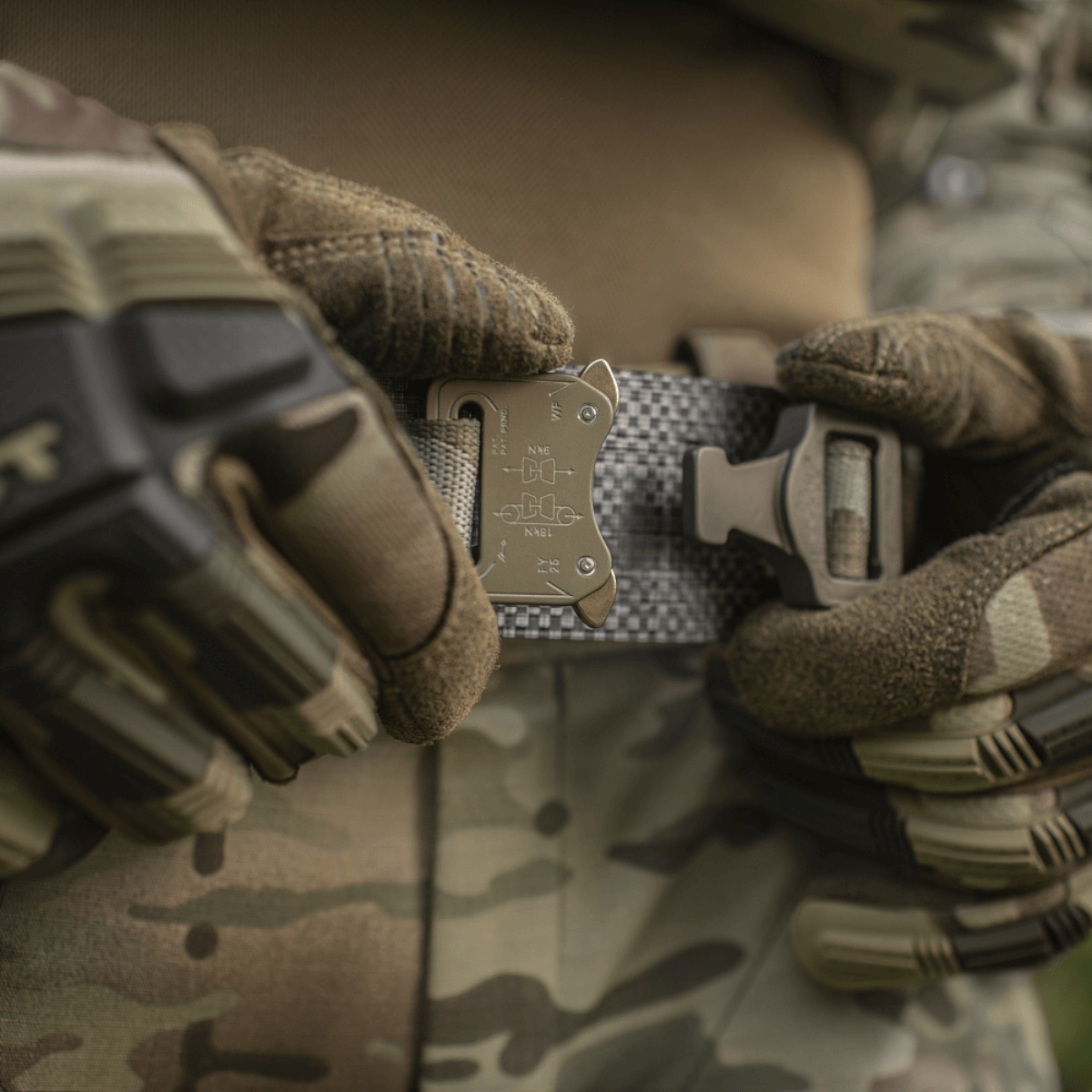 M-Tac Tiger Bælte Cobra Buckle i brug af militærpersonel med handsker, taktisk udstyr og camouflagetøj.