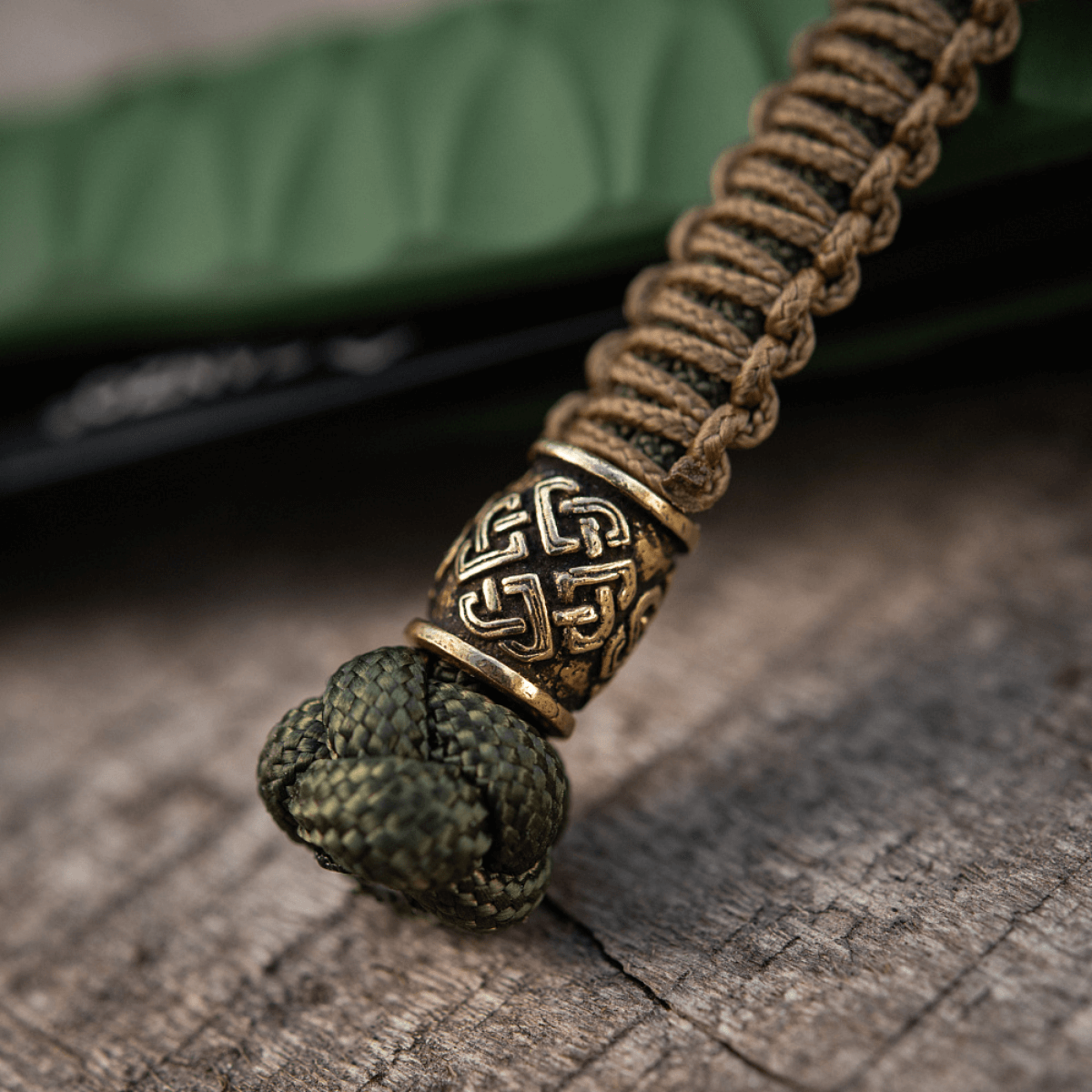 M-Tac Knife Lanyard Celtic i flettet paracord med keltisk mønster, knivtilbehør på trælignende overflade.