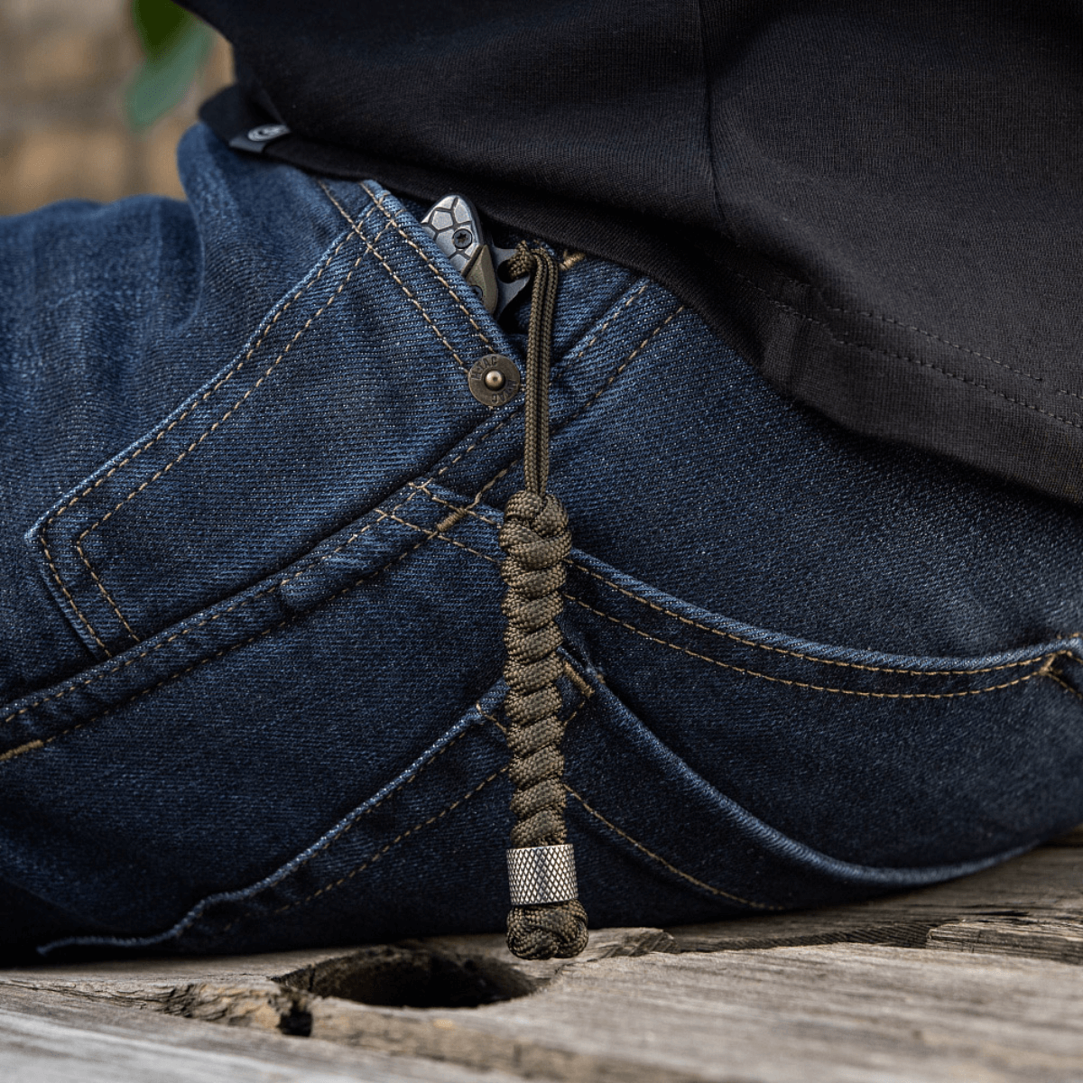 M-Tac Viper Lanyard Stainless Steel i jeanslomme, praktisk paracord til hurtig knivadgang, stilfuldt rustfrit stålperle design.