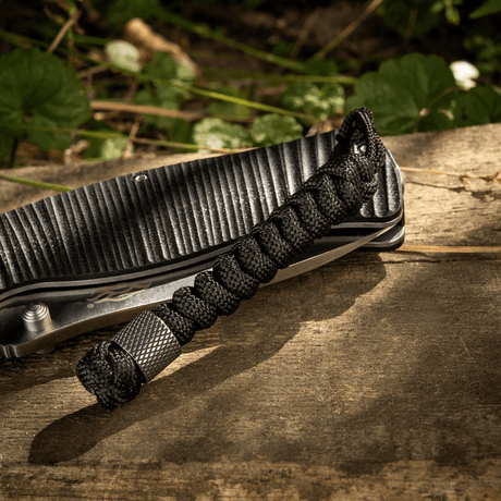 M-Tac Viper Lanyard Stainless Steel with braided paracord and Viper bead, stylish knife accessory, black lanyard on wooden background.