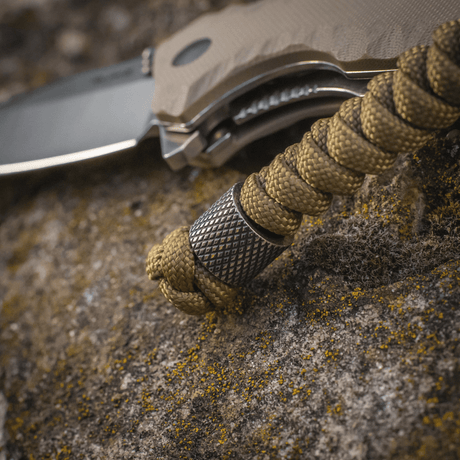 M-Tac Viper Lanyard Stainless Steel with braided paracord and stainless steel bead on a knife, stylish accessory for quick access.