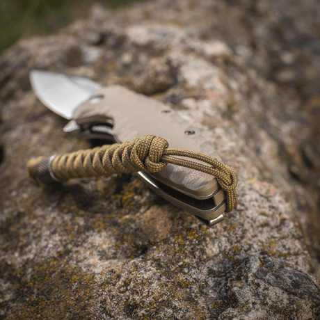M-Tac Viper Lanyard Stainless Steel attached to knife, shown on a stone surface. Flexible extension in braided paracord.