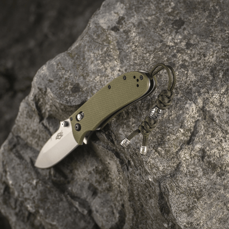 M-Tac Zeus Stainless Steel Lanyard with braided paracord and decorative bead for quick access to a knife on a stone background.