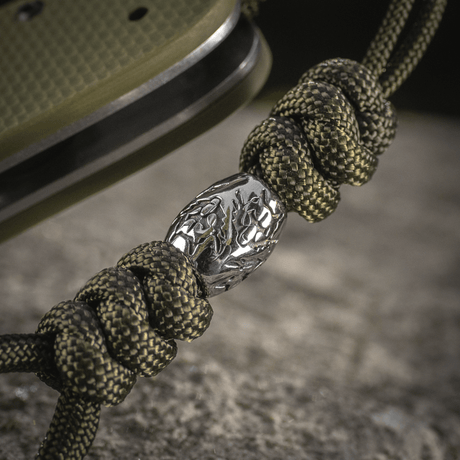 M-Tac Zeus Stainless Steel Lanyard with braided paracord and decorative metal bead on a knife, suitable for quick access.