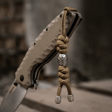 M-Tac Zeus Stainless Steel Lanyard with braided paracord and decorative beads on a knife, used for quick access to gear.