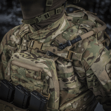 M-Tac Sturm Elite Gen.II in camouflage pattern with MOLLE system and built-in hydration system, shown in a field setup.