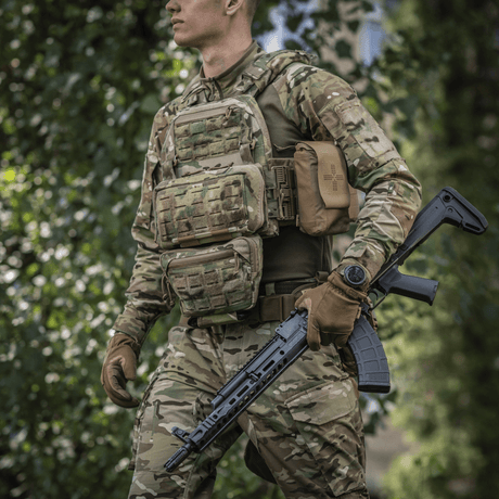 Person in camouflage uniform wearing M-Tac Admin Pouch Large Elite and holding a tactical rifle in a forest.