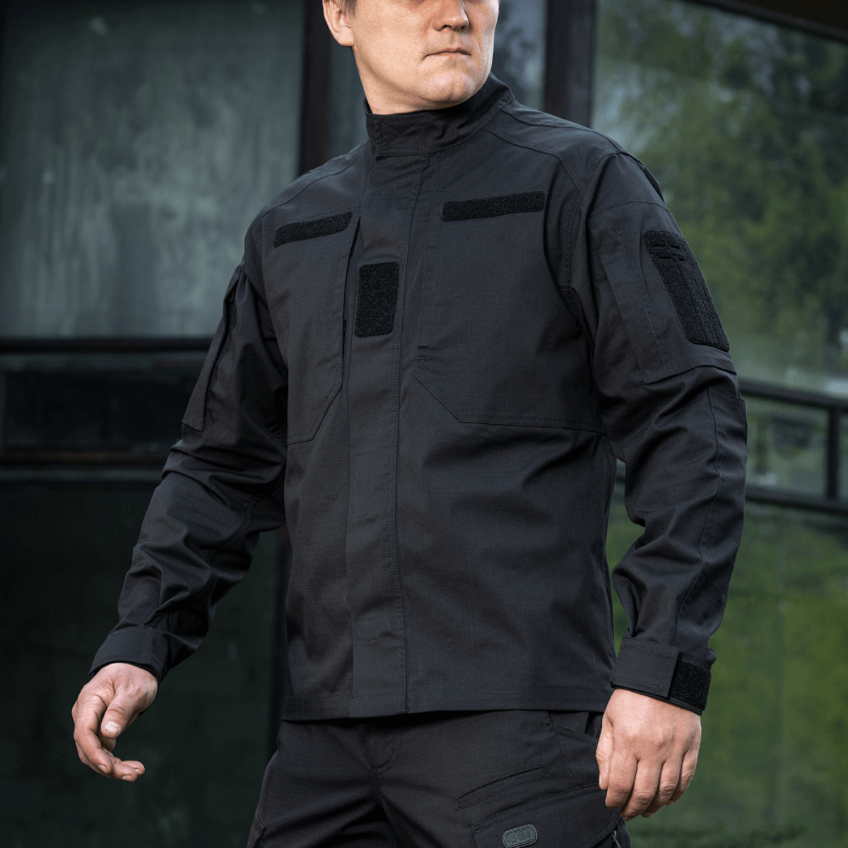 Mand i sort M-Tac Jakke Patrol Flex med taktisk design, Velcro-paneler og lommer, perfekt til praktisk brug.