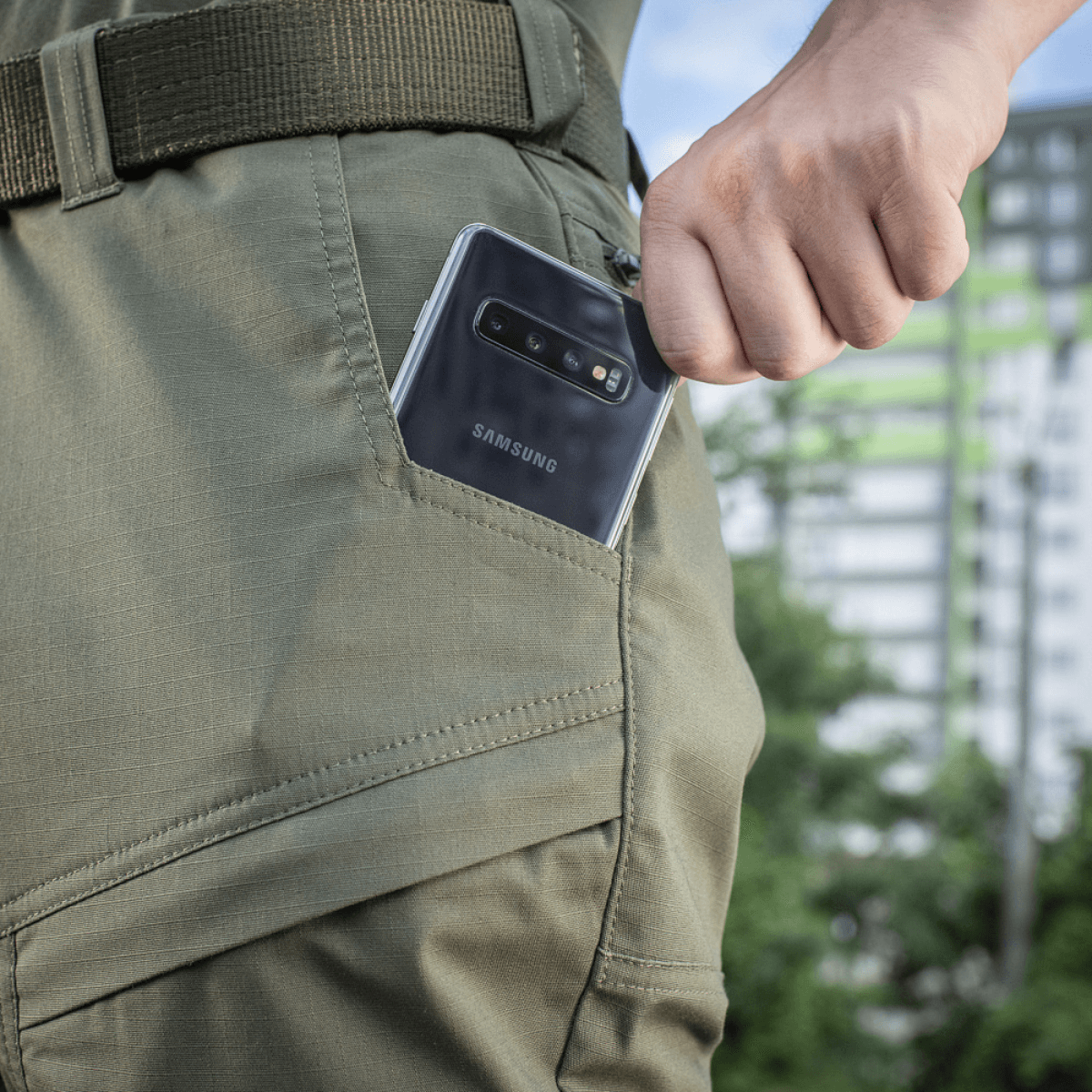 En person tager en telefon op af lommen på M-Tac Tactical Bukser Patrol Gen II Flex i udendørs omgivelser.