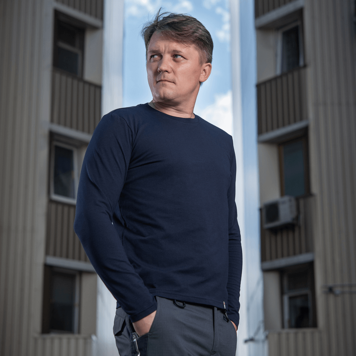 Mand iført M-Tac Long-sleeve T-shirt 93/7 fremhæver muskelkonturer mod en bybaggrund.