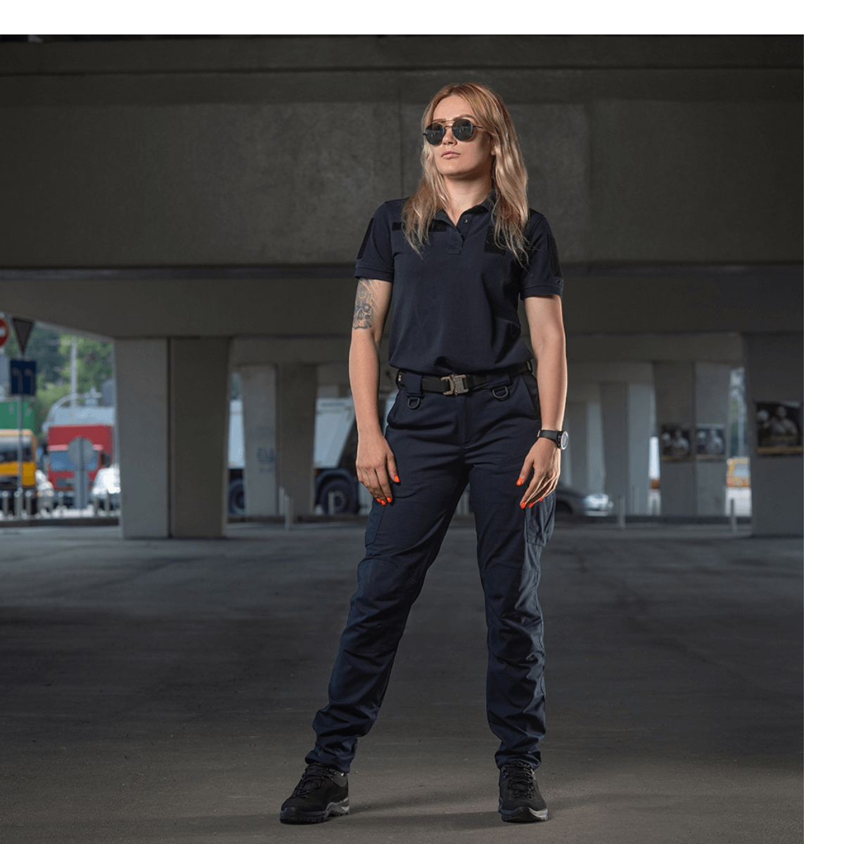 Kvinde iført M-Tac Bukser Aggressor Dame Flex under en viadukt, ideel til træning eller arbejde, beskytter mod vand og snavs.