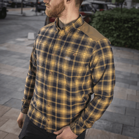 Mand iført M-Tac Redneck Skjorte i navy blå/gul plaid med justerbare ærmer og forstærkede skuldre på fortovet.