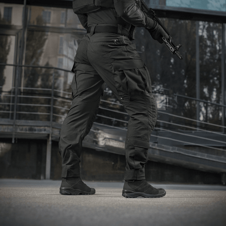 Mand iført M-Tac Bukser STURM NyCo Extreme Gen.II med fleksible indlæg, designet til taktisk brug, fotograferet udendørs.