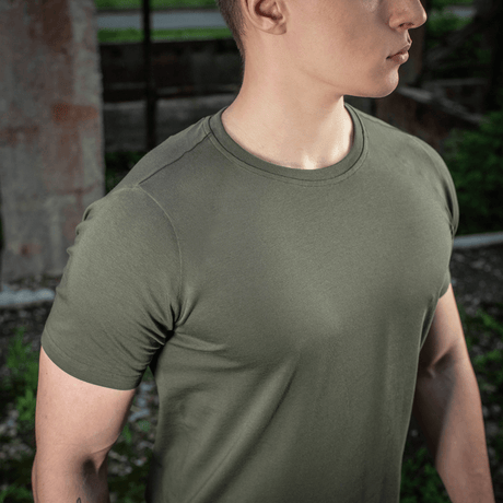 Mand iført M-Tac T-shirt 93/7 Summer i naturen, fokuserer på let og åndbar kvalitet til sommerdage.