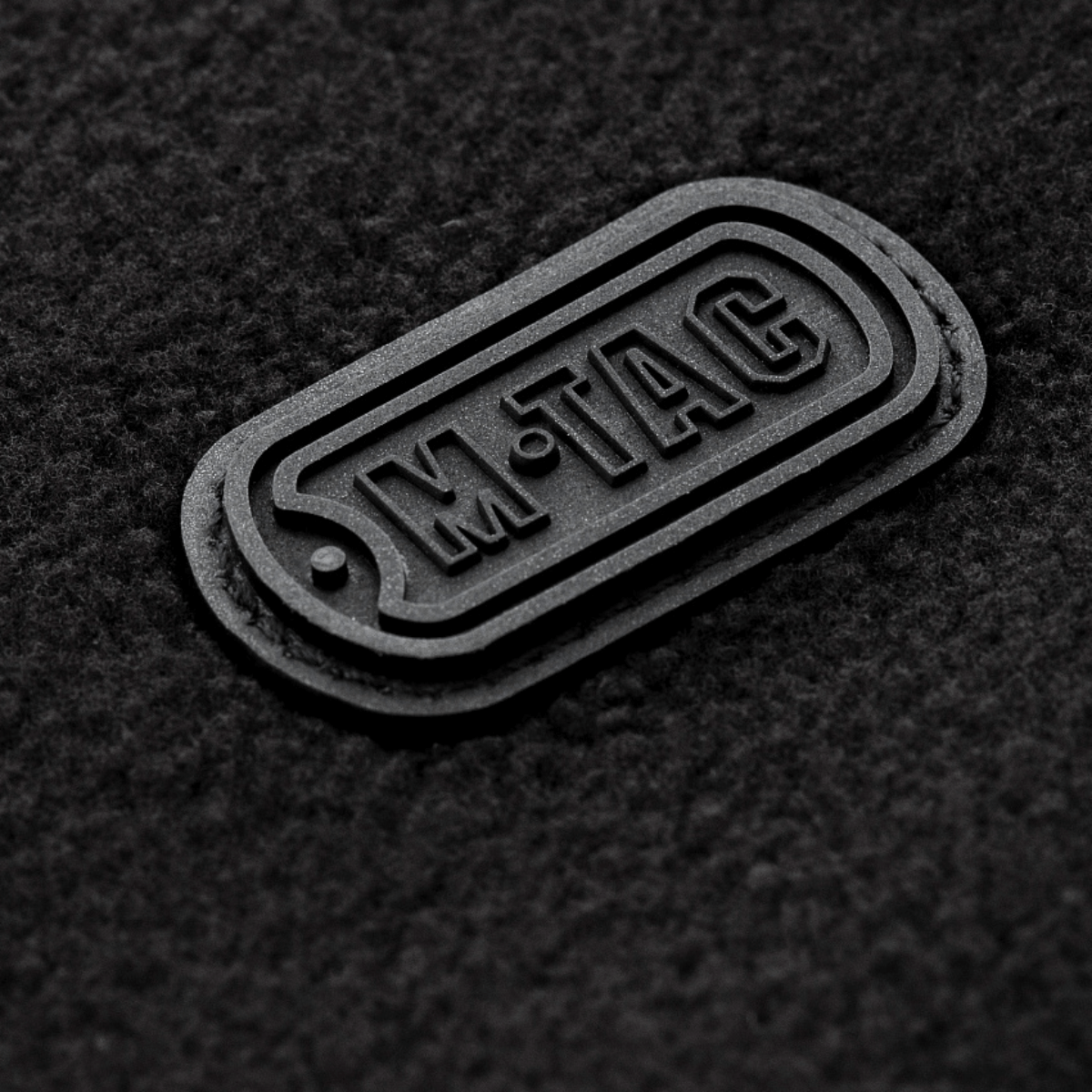 M-Tac Alpha Microfleece Jakke Gen.II logo detalje på fleeceoverflade, moderne jakke til taktisk og outdoor brug i koldt vejr.