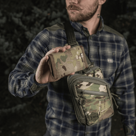 Man holding M-Tac Pung Elite Gen.II in camouflage pattern, made from Cordura 500D with YKK zippers, in a forest environment.