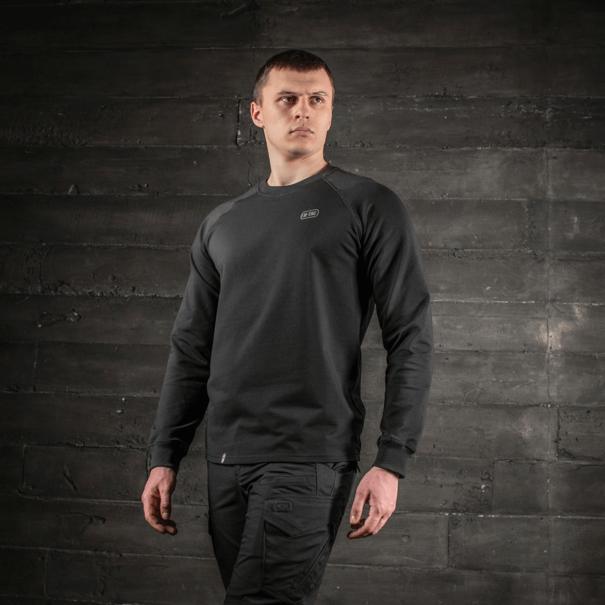 Mand iført M-Tac Raglan Athlete sweatshirt i sort, minimalistisk design med rund hals og raglanærmer, ideel til sport og hverdag.