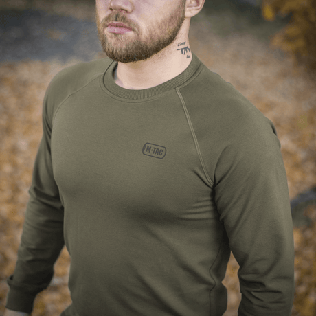 M-Tac Raglan Athlete in olive green with raglan sleeves, ideal for everyday wear and sports, shown outdoors among autumn leaves.