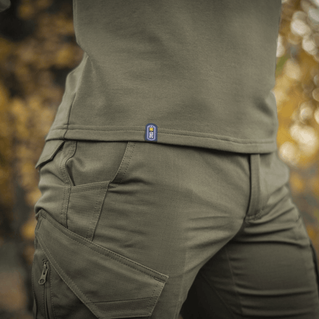 Person wearing M-Tac Raglan Athlete sweatshirt in olive, close-up of minimalist design with raglan sleeves and stretch cuffs.
