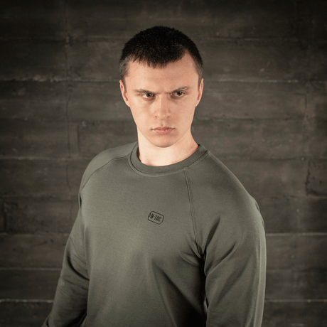 Man in M-Tac Raglan Athlete sweatshirt in olive, showing versatility and minimalist design with raglan sleeves for freedom of movement.