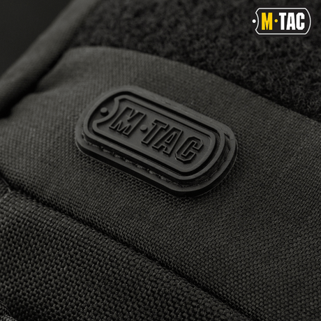 Close-up of M-Tac logo on M-Tac Buckler Bag Elite, a black tactical bag with MOLLE system and hidden weapon compartment.