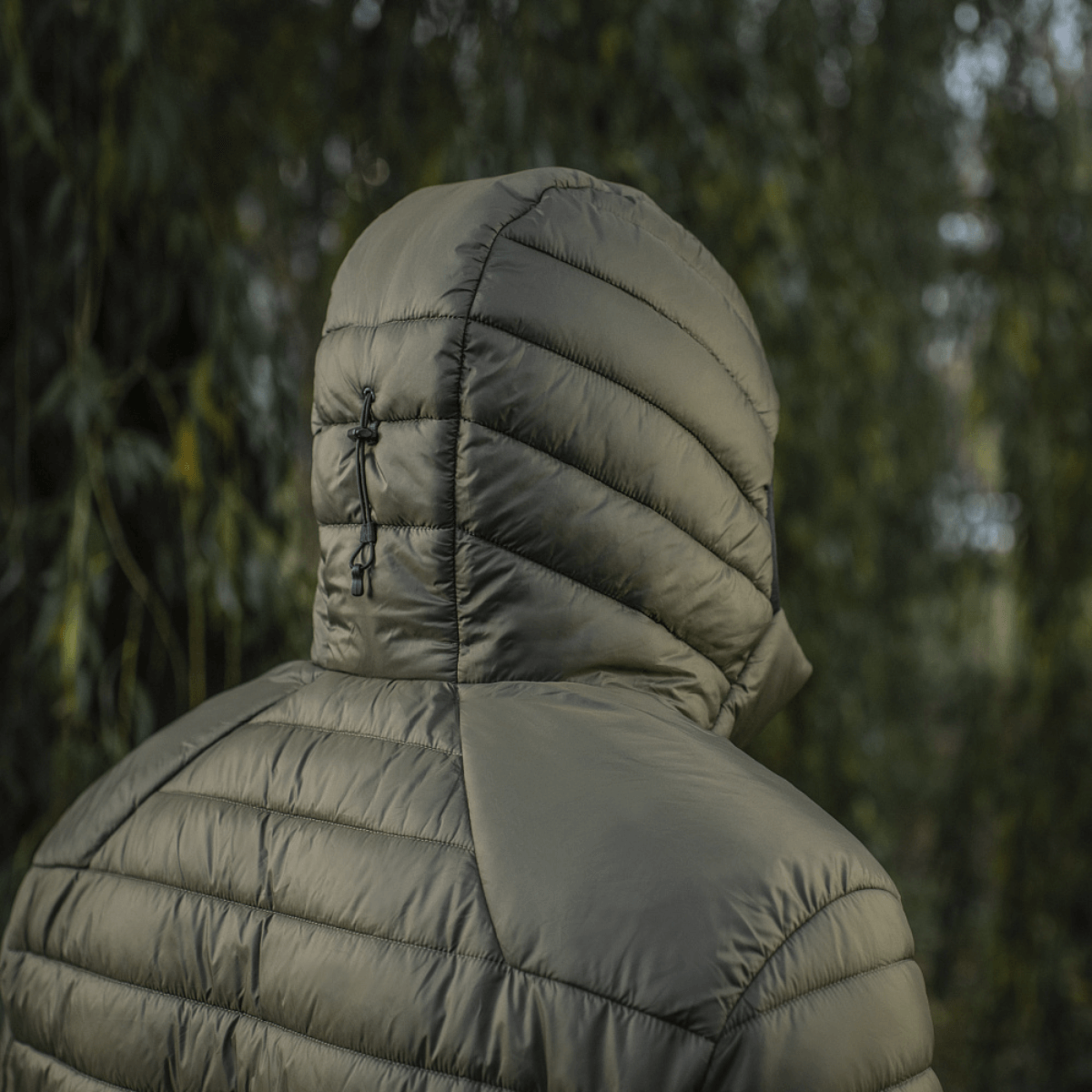 M-Tac Stalker Gen.III Jakke med justerbar hætte for optimal bevægelsesfrihed og varme i overgangssæsonen, set bagfra i naturen.