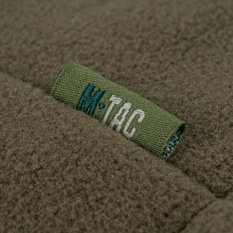 Nærbillede af M-Tac Combat Fleece Polartec Jakke med mærke detalje, der viser høj kvalitet og avanceret materiale i militærgrøn farve.