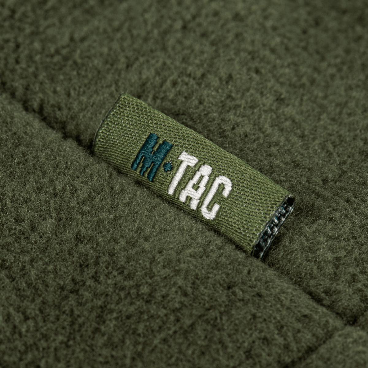 Nærbillede af M-Tac Combat Fleece Polartec Jakke i grøn med synligt M-Tac logo.
