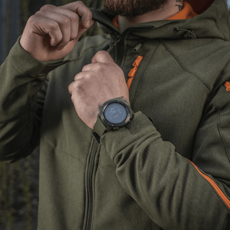 Image of M‑Tac Multifunctional Tactical Watch worn by a person in a green jacket, highlighting watch design and features for outdoor activities and military use