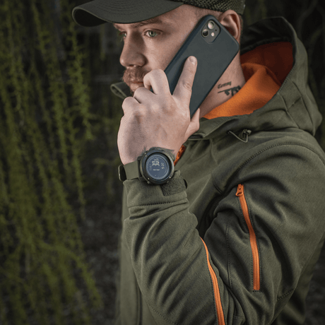 Man wearing M‑Tac Multifunctional Tactical Watch while talking on phone, forest background