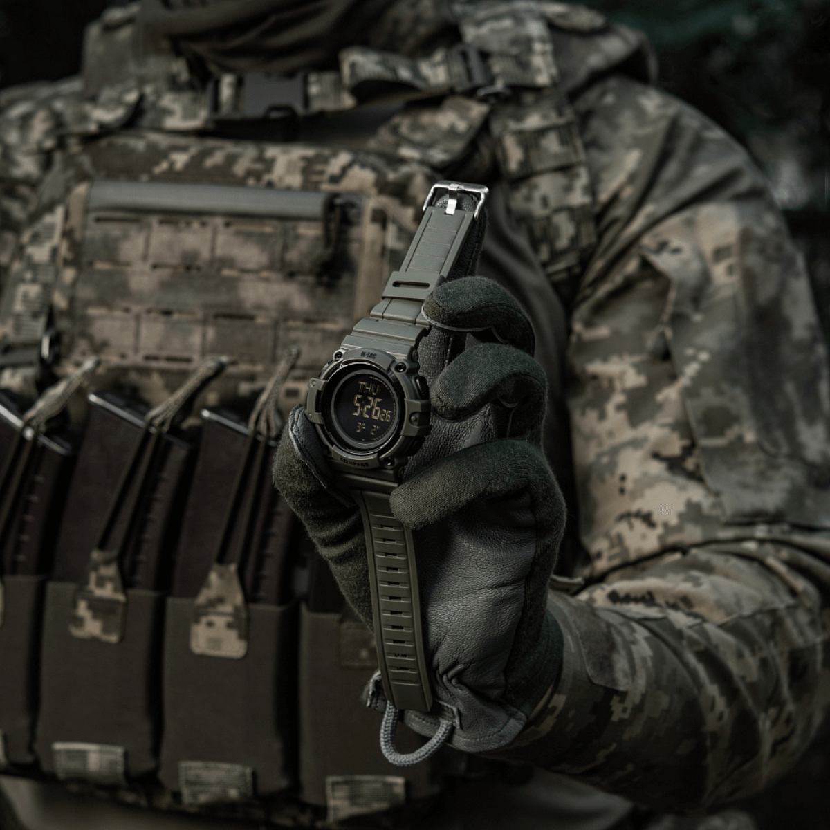 M-Tac Tactical Ur med Kompas 2233 holdt af taktisk klædt person, viser robust urdesign egnet til outdoor og daglig brug