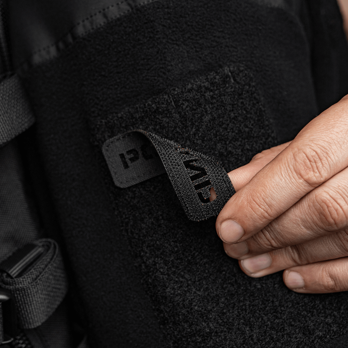 Person fastgør M‑Tac Patch Poland End-to-End 25x80 til tøj med velcro, viser detalje af laser cut inskription og holdbart Cordura 500D materiale.