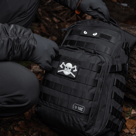 M-Tac Bearded Skull 3D PVC Patch attached to a black backpack with Velcro in a tactical outdoor setting.