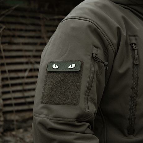 M-Tac Cat Eyes 3D PVC Patch on jacket sleeve in a tactical environment, showing reflective and fluorescent design, attached with Velcro.