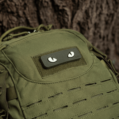 M-Tac Cat Eyes 3D PVC Patch on green backpack next to a tree.