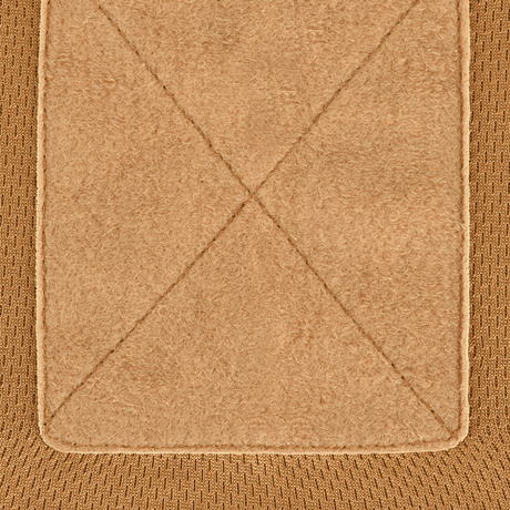 Detaljeret nærbillede af beige stoftekstur med krydsende syningslinjer, der viser materialekvalitet og design.