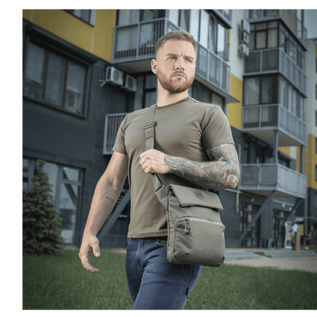 Man wearing M-Tac Konvert Bag Elite in a gray urban setting, a modern tablet-style bag made of durable Cordura.