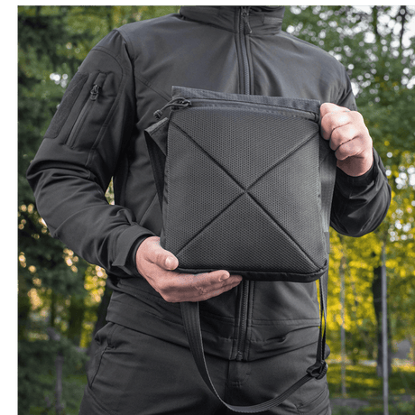 M-Tac Konvert Taske Elite in Cordura 500D and Hex 1000D, with tablet-style design and adjustable shoulder strap, held by a person in nature.