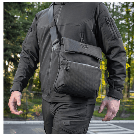 Man wearing M-Tac Konvert Taske Elite in Cordura material, with adjustable shoulder strap and tablet-style design, seen outdoors.