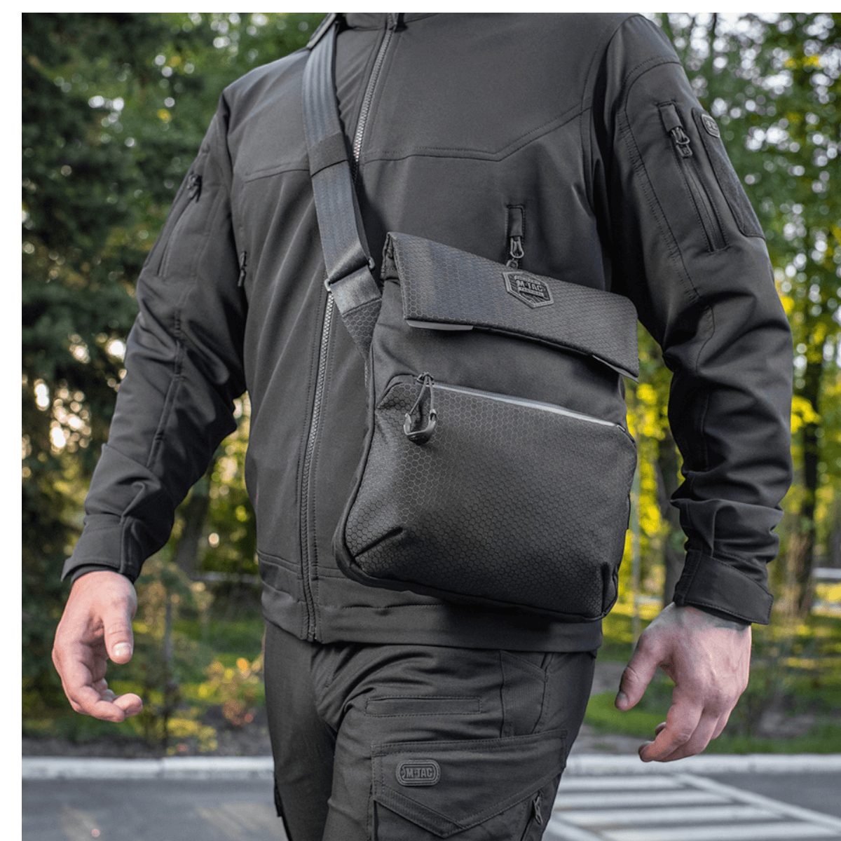Mand bærer M-Tac Konvert Taske Elite i Cordura materiale, justerbar skulderrem og tablet-design, set udefra i et udendørs miljø.