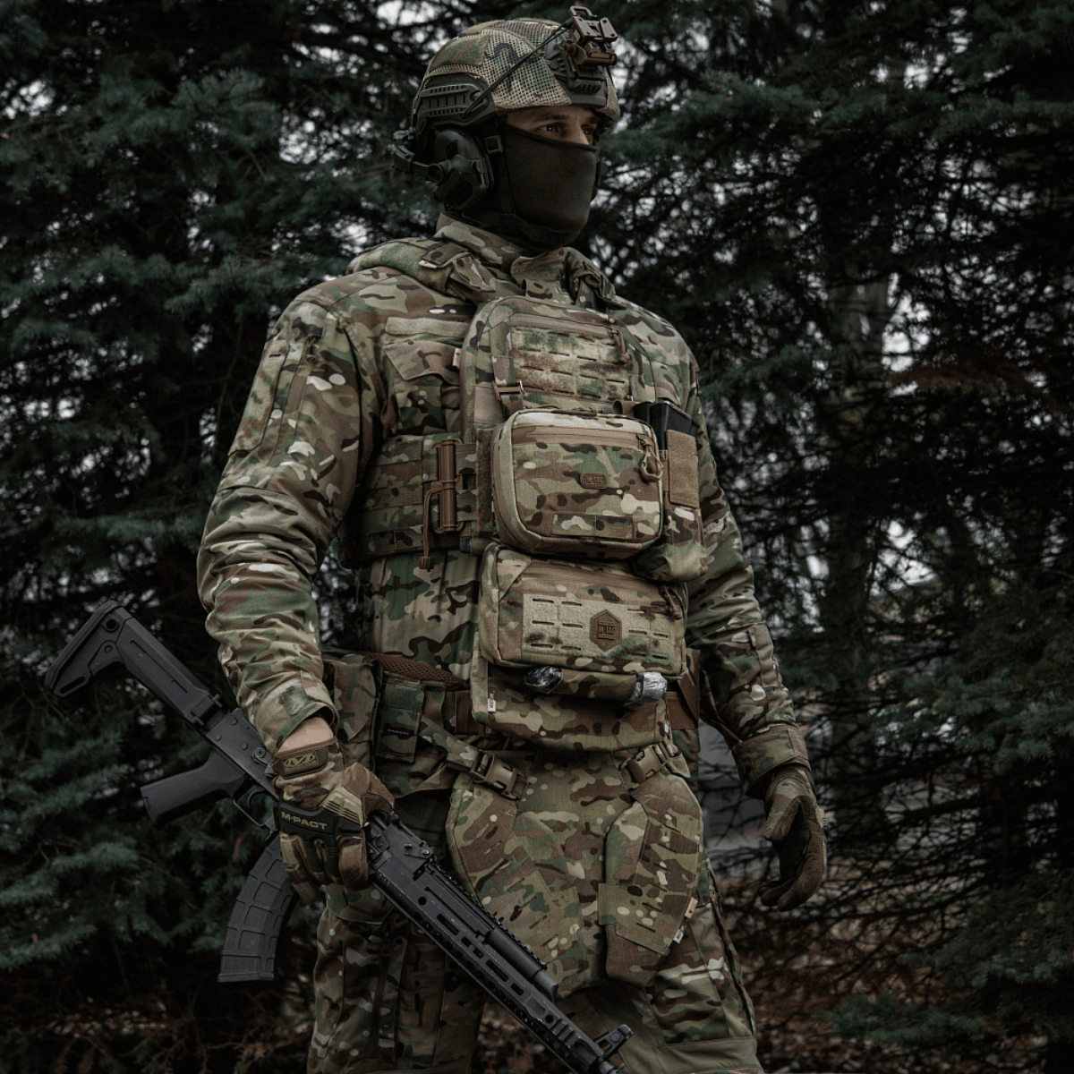 Taktisk soldat med M-Tac organizer pouch Elite fastgjort til vest via M.O.L.L.E.-systemet i skovklædt område.