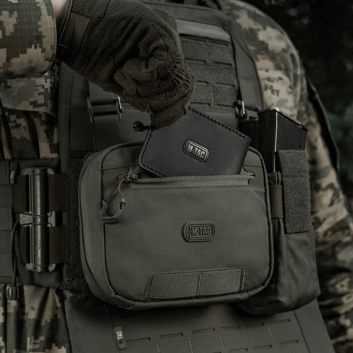 M-Tac organizer pouch Elite fastgjort til taktisk vest med M.O.L.L.E.-system, holder nødudstyr og værktøjer, åben ved 90 grader.