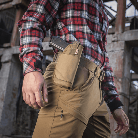 Person with M-Tac Universal Tactical Holster Elite Right mounted on belt in outdoor setting.