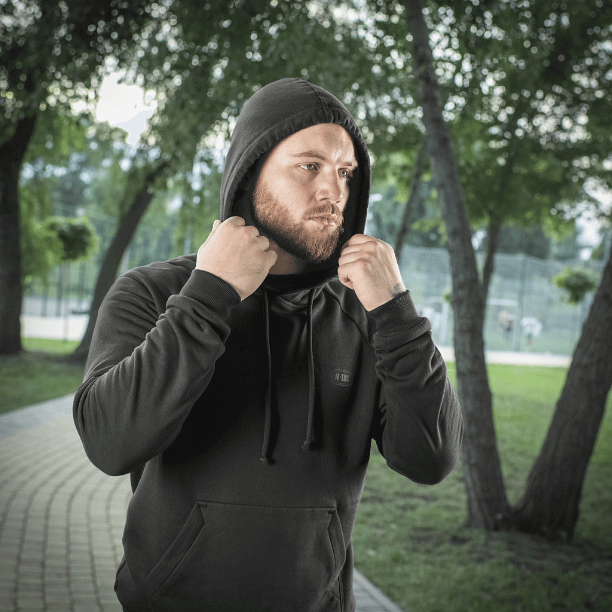 Mand i sort M-Tac Hættetrøje Cotton Raglan i park, klar til aktivitet