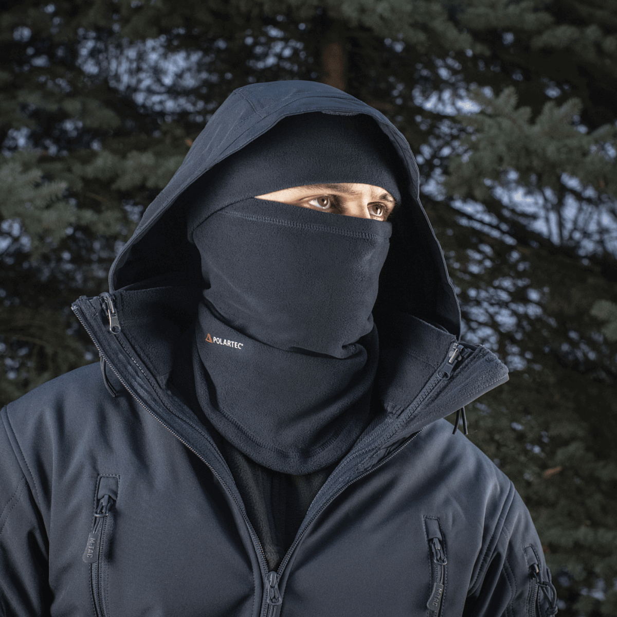 Mand iført M-Tac Anatomisk Tube Scarf med Snor Polartec som ansigtsmaske i skovmiljø. Polartec fleece giver varme og beskyttelse.