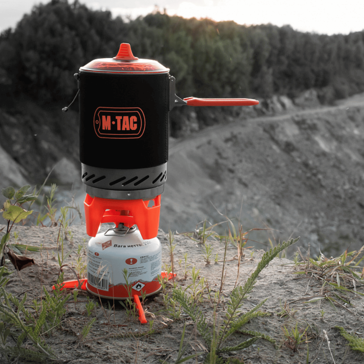 M-Tac Gasbrænder med Kedel i brug på klippe, ideel til camping og vandreture, kompakt og energieffektiv madlavningssystem.