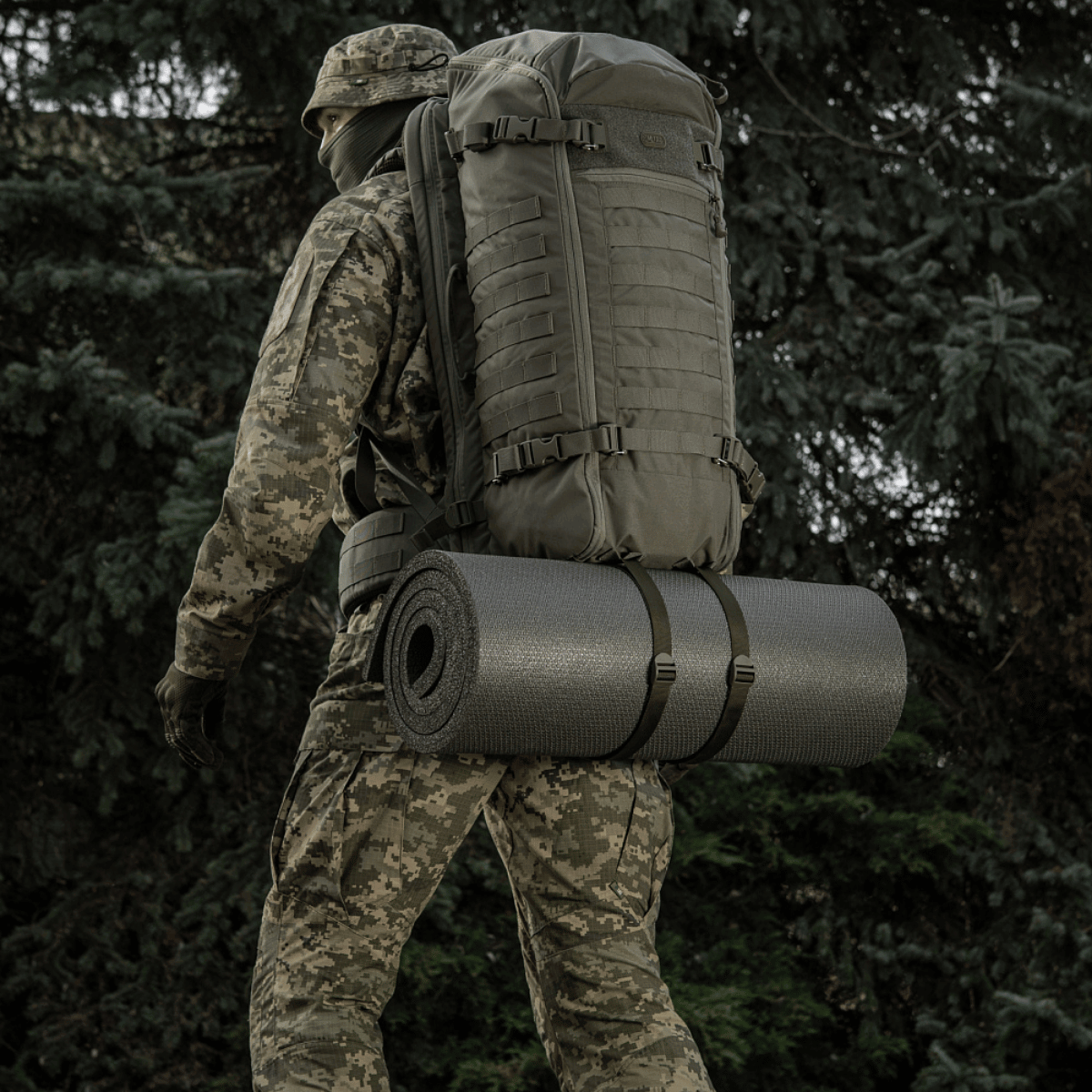 Soldat med rygsæk og M-Tac Liggeunderlag 20 mm (60x180 cm) i naturen til friluftsliv og ekstremt klima.