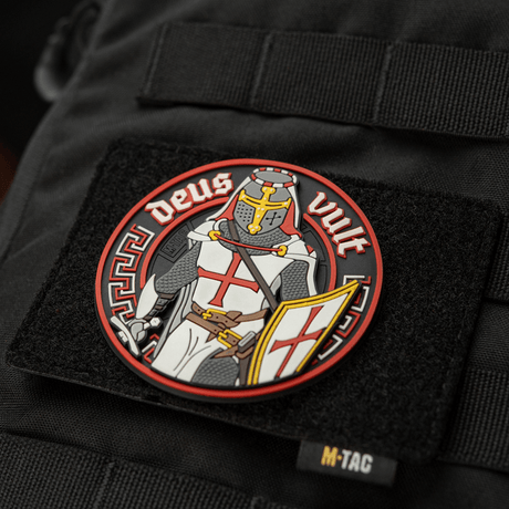 M-Tac Deus Vult 3D PVC Patch on a black bag, shows a knight with the text 'Deus Vult', attached with Velcro. Ideal for outdoor use.